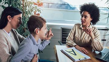 Teacher teaching two students sign language